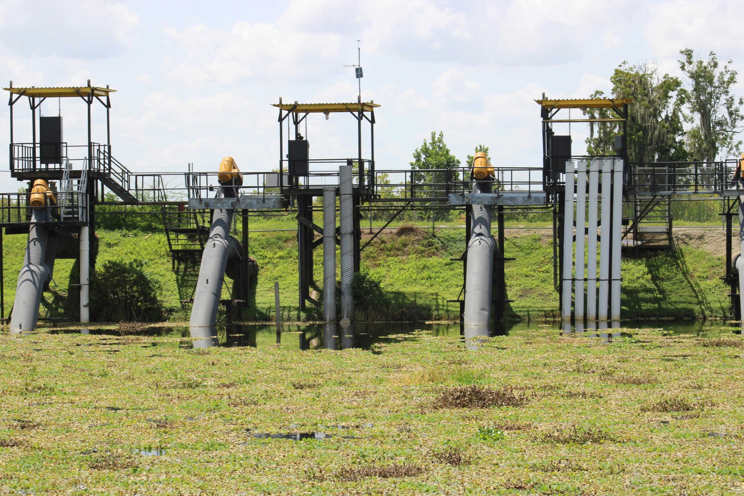 Water lock system with pipes and steel structures in a grassy field.
