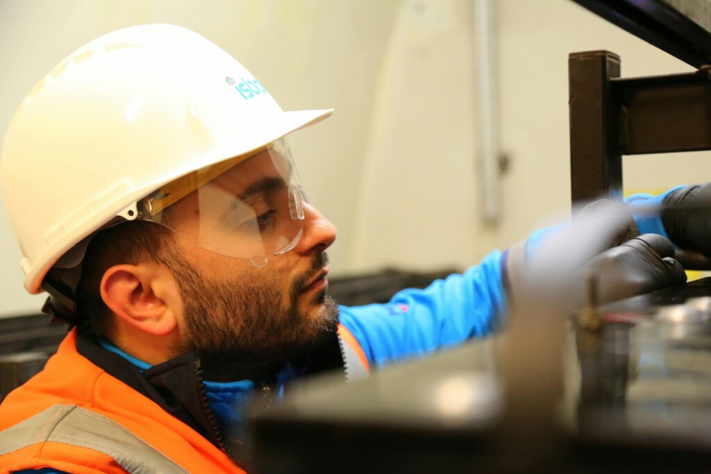 Close-up of a construction worker wearing safety gear while focusing on a task indoors.